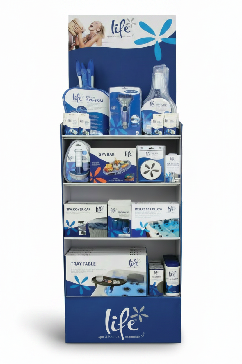The image shows a tall, freestanding retail display unit branded “Life™ Spa & Hot Tub Essentials” in blue and white. The display consists of multiple shelves filled with neatly arranged packaged products.

Top Section: A branded header panel featuring a lifestyle image and blue floral design.
Upper Shelves: Hanging and boxed items including spa skimmers, brushes, scoop tools, and small accessories in uniform blue and white packaging.
Middle Shelves: Larger boxed items such as a spa bar tray table, spa disc 
